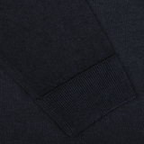 Close-up of a dark fabric sleeve with a ribbed cuff. The texture of the Navy Blue Melange Merino Wool Crewneck by Daniele Fiesoli and the stitching details are clearly visible—expertly crafted by knitwear specialists for a regular fit.