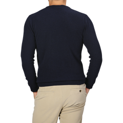 A person stands with their back to the camera, donning a Navy Blue Wool Cashmere Crewneck from Daniele Fiesoli and beige pants.