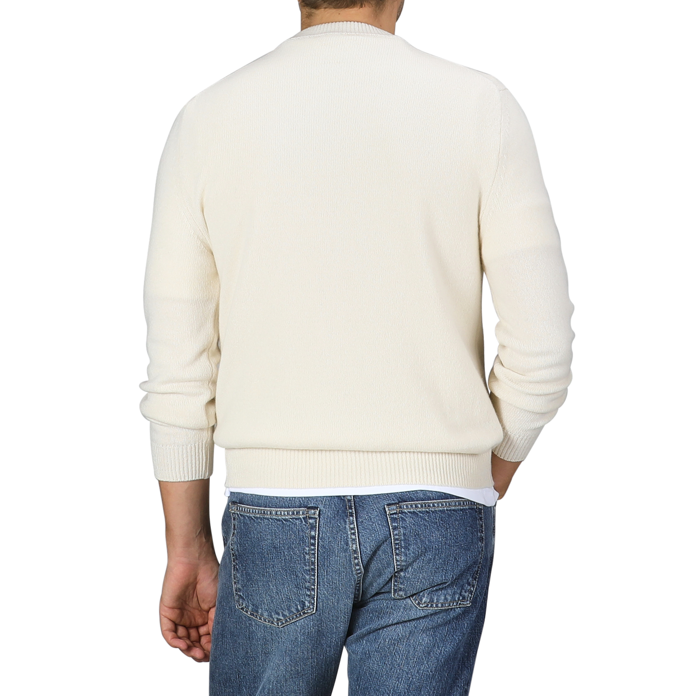 A person wearing the Nuvola Ecru Cashmere Crewneck Sweater by Daniele Fiesoli and blue jeans, facing away.