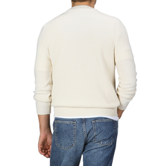 A person wearing the Nuvola Ecru Cashmere Crewneck Sweater by Daniele Fiesoli and blue jeans, facing away.