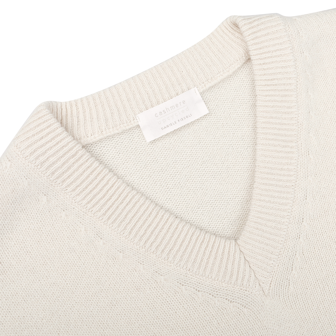 Close-up of the Nuvola Ecru Cashmere V-Neck Sweater by Daniele Fiesoli, crafted from upcycled cashmere in a beige hue, with a visible label on the inside collar.