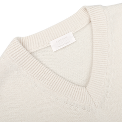 Close-up of the Nuvola Ecru Cashmere V-Neck Sweater by Daniele Fiesoli, crafted from upcycled cashmere in a beige hue, with a visible label on the inside collar.