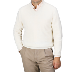 A person wearing the Nuvola Ecru Cashmere V-Neck Sweater by Daniele Fiesoli over a light-colored shirt and beige pants, with hands in pockets, stands against a plain background.