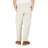 Rear view of a person wearing De Bonne Facture's undyed heavy cotton drill balloon trousers and brown suede shoes, standing against a white background.