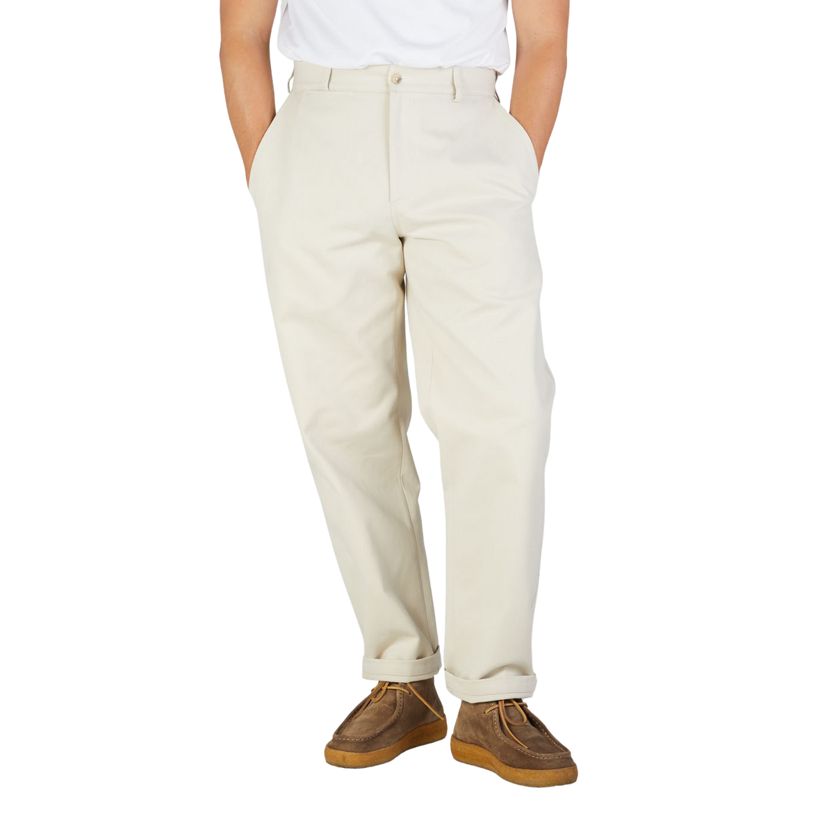 A close-up of a person wearing De Bonne Facture's Undyed Heavy Cotton Drill Balloon Trousers and brown suede shoes, standing against a plain background.