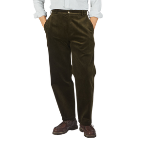 A man wearing De Bonne Facture Dark Olive Cotton Corduroy Balloon trousers and a white shirt.