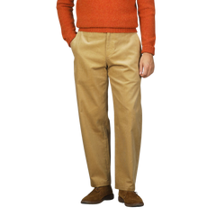 Person wearing a gold mustard cotton corduroy balloon trousers by De Bonne Facture with hands in pockets, standing against a plain background.