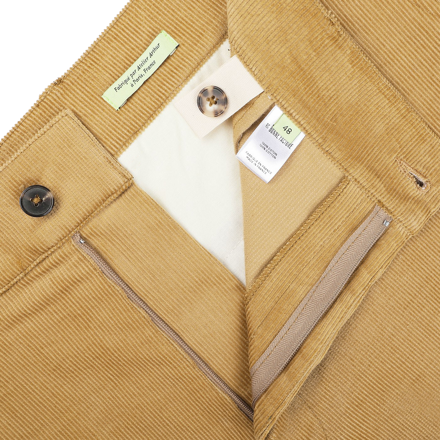 Close-up of open Gold Mustard Cotton Corduroy Balloon Trousers by De Bonne Facture, highlighting the zipper, button, waistband labels, and inner lining, exemplifying classic workwear pieces.