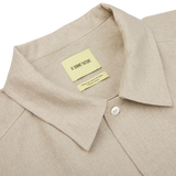 Close-up of a De Bonne Facture oatmeal beige linen canvas painter's jacket collar with a sewn-in label reading "le bonheur toute".