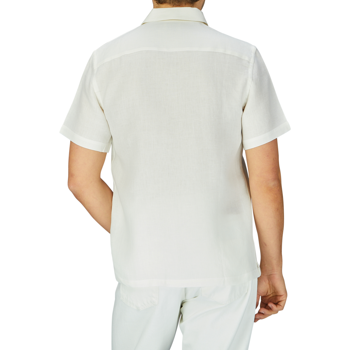 Rear view of a person wearing an Off White Linen Floral Embroidered Shirt by De Bonne Facture and white pants against a plain background.