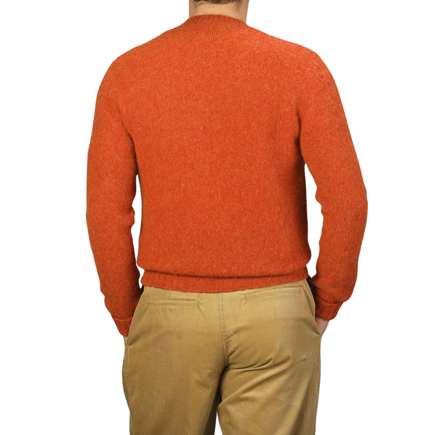 A person wearing a De Bonne Facture Orange Shetland Shaggy Dog Sweater and beige khaki pants, seen from behind. The background is plain and light-colored.