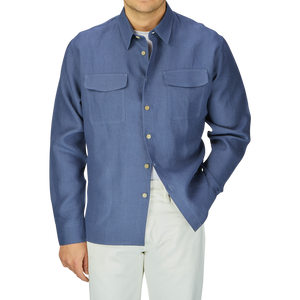 Man wearing a De Bonne Facture Pastel Blue Belgian Linen Two Pocket Overshirt with a shirt collar and white pants, cropped at the neck and just above the knees.