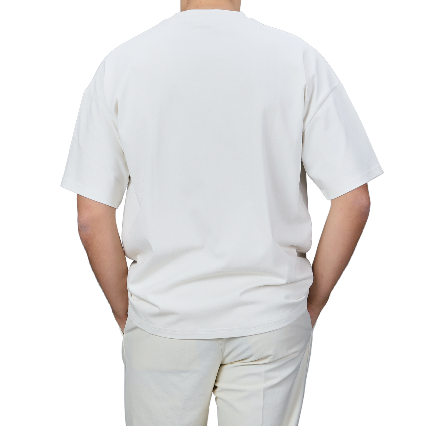 A person wearing an oversized Undyed Printed Cotton Jersey T-Shirt by De Bonne Facture and pants is shown from the back against a neutral background.