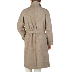 The back view of a man wearing a De Bonne Facture Undyed Wool Herringbone Grandad Coat, exuding a traditional yet contemporary style.