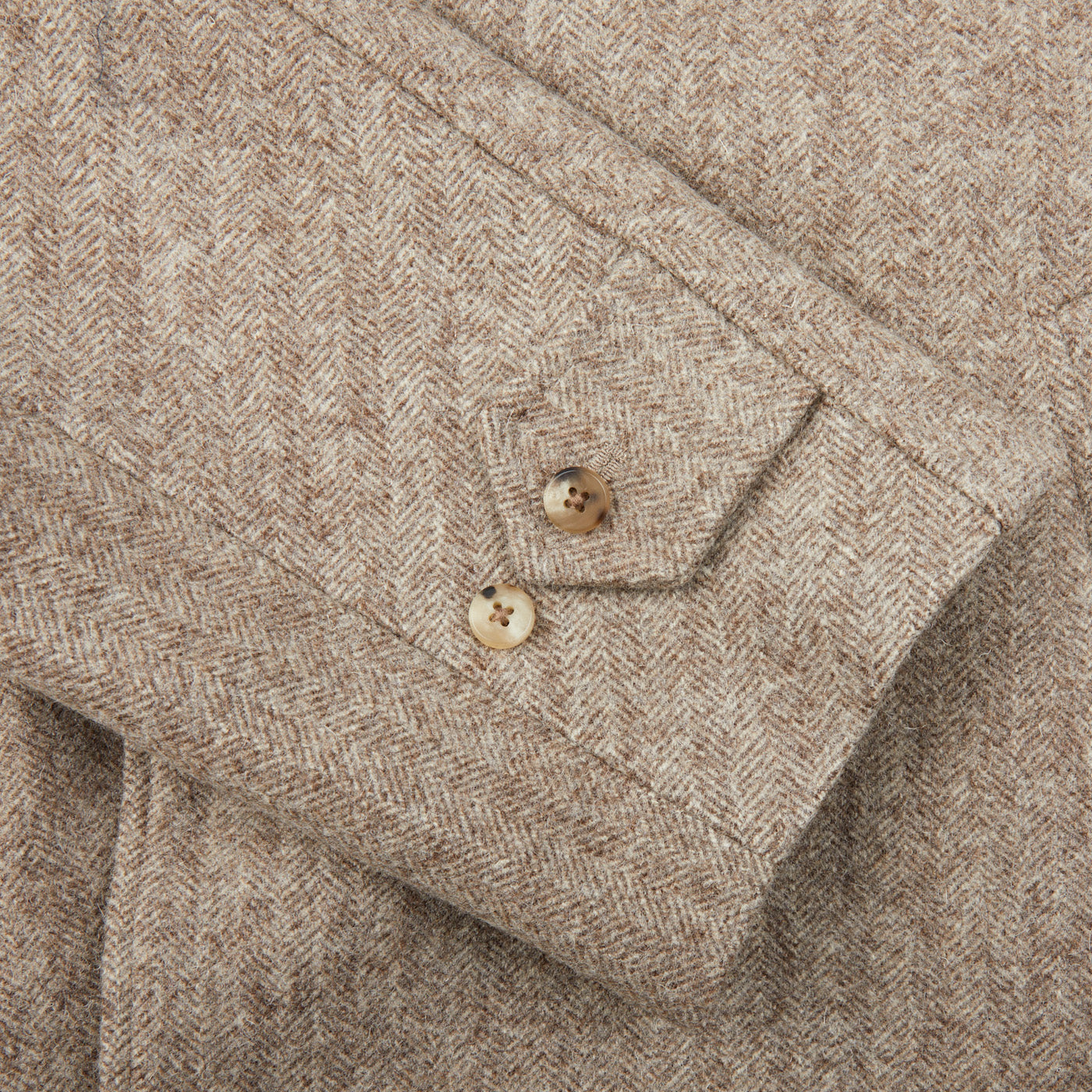 A close up of a Undyed Wool Herringbone Grandad Coat by De Bonne Facture, featuring a traditional yet contemporary style.