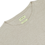 Close-up of an oversized oatmeal beige linen jersey t-shirt with a label showing the brand "De Bonne Facture" and additional details, set against a white background.