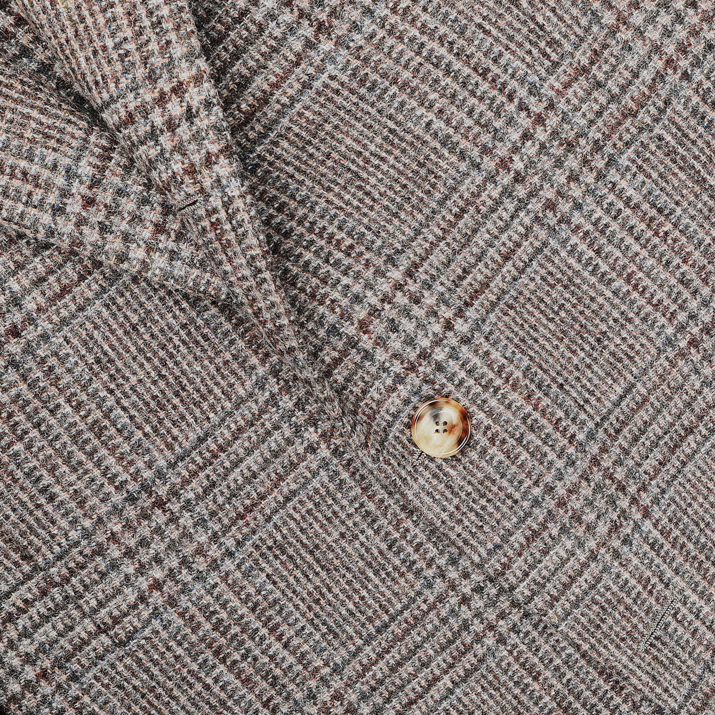 Close-up of the Brown Checked Wool Tweed Posillipo Blazer by De Petrillo, showcasing its fabric with shades of brown and adorned with a single tan button.