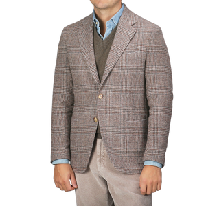 A man is sporting the Brown Checked Wool Tweed Posillipo Blazer by De Petrillo over a brown sweater and a blue button-up shirt, paired with light-colored corduroy pants.