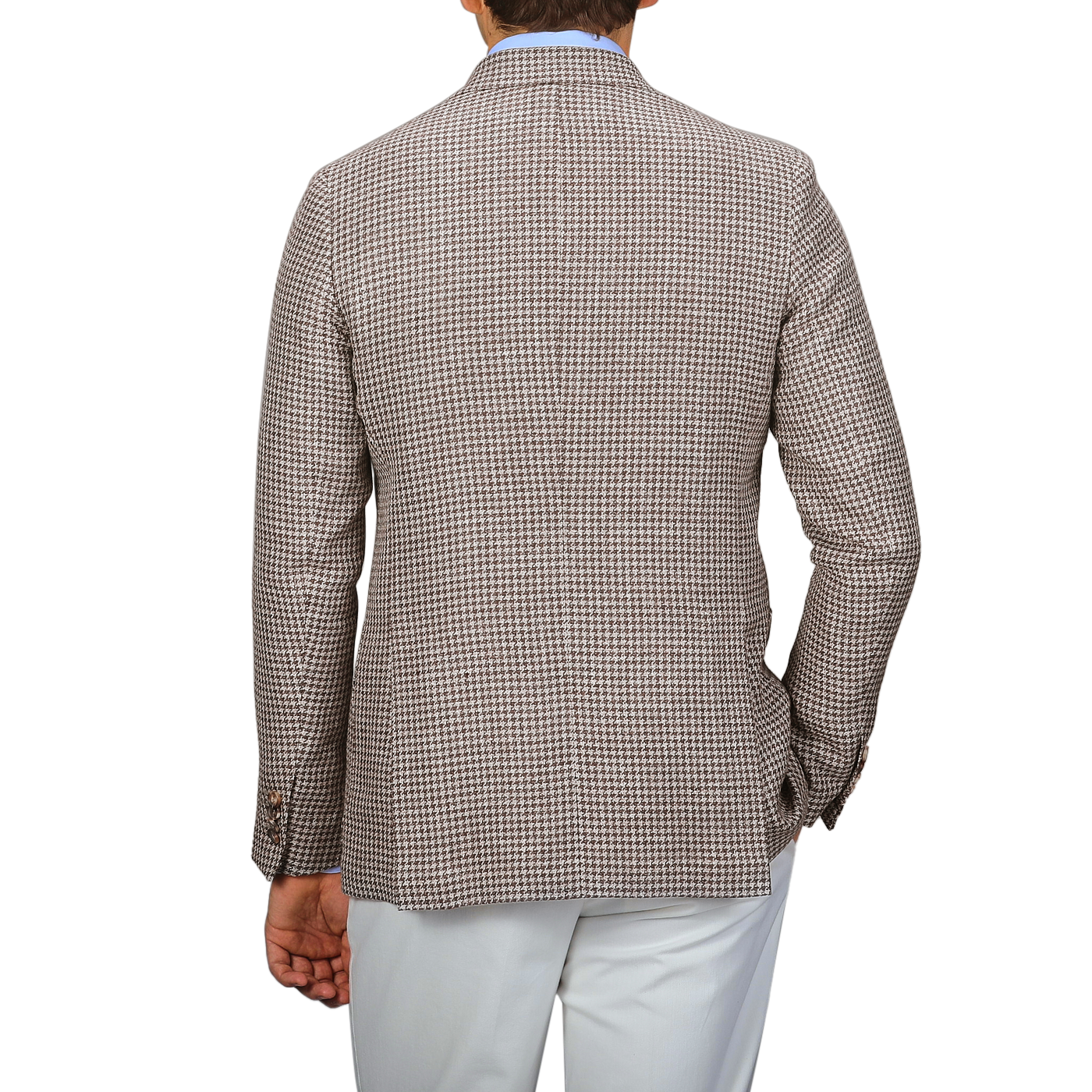 A person exudes classic elegance in the meticulously tailored De Petrillo Brown Houndstooth Wool Linen Posillipo Blazer paired with crisp white pants, viewed from the back.