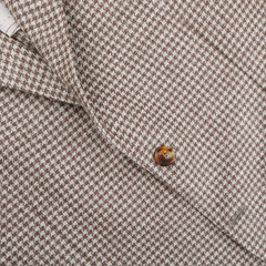 Close-up of a brown houndstooth-patterned fabric, highlighting the exquisite tailoring of De Petrillo's Brown Houndstooth Wool Linen Posillipo Blazer with a button and lapel.