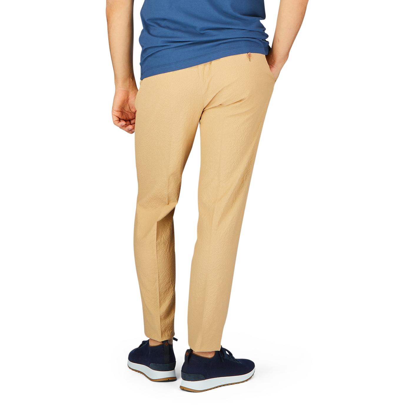 Lower half of a person standing, wearing De Petrillo Caramel Cotton Linen Seersucker Drawstring Trousers and blue sneakers.