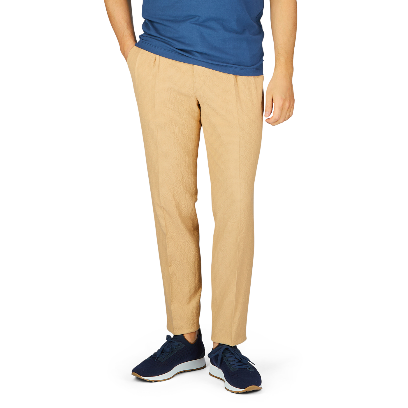 A person wearing a blue t-shirt, De Petrillo caramel cotton linen seersucker drawstring trousers, and blue sneakers, cropped at the waist.