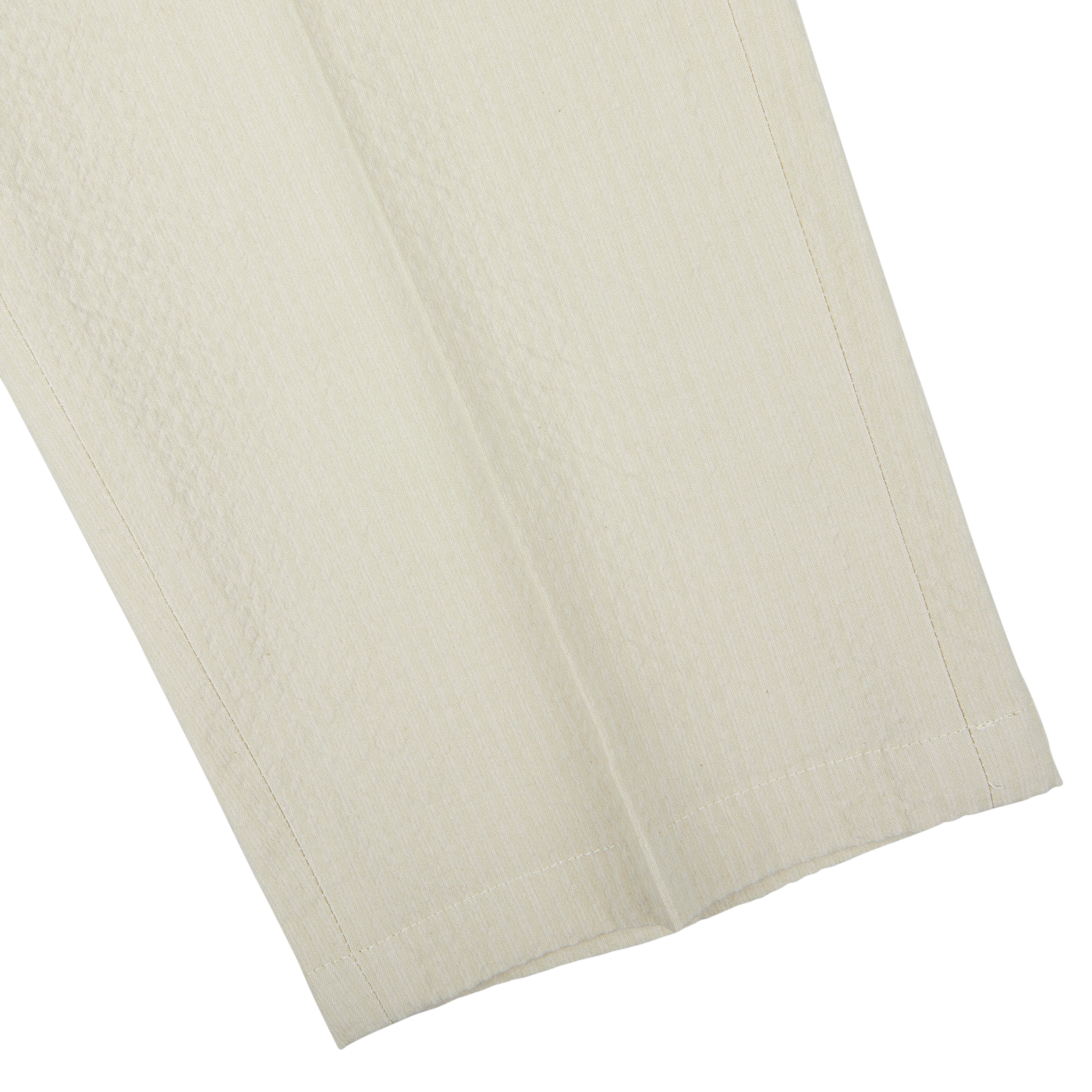 Close-up of a folded cream De Petrillo trousers made of cotton seersucker fabric with textured pattern on a white background.