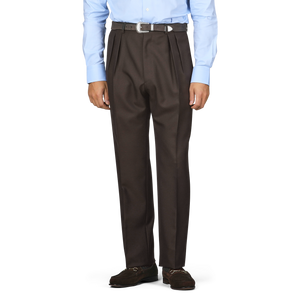 The individual is wearing a light blue shirt paired with dark brown wool twill trousers from De Petrillo, accompanied by a black belt and stylish brown loafers.