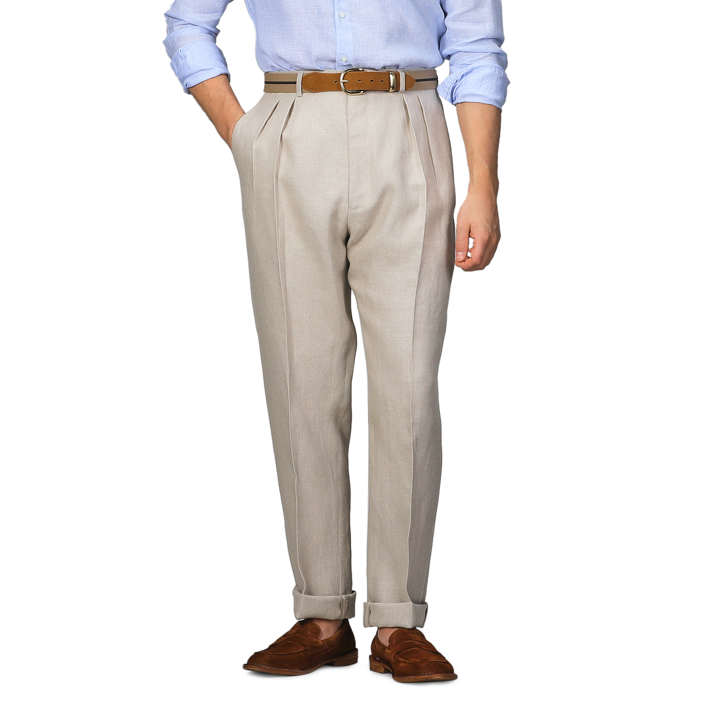 A person wearing De Petrillo Sand Beige Irish Linen Modello E Trousers, a brown belt, a light blue shirt, and brown loafers stands confidently with hands in pockets, exuding casual elegance.