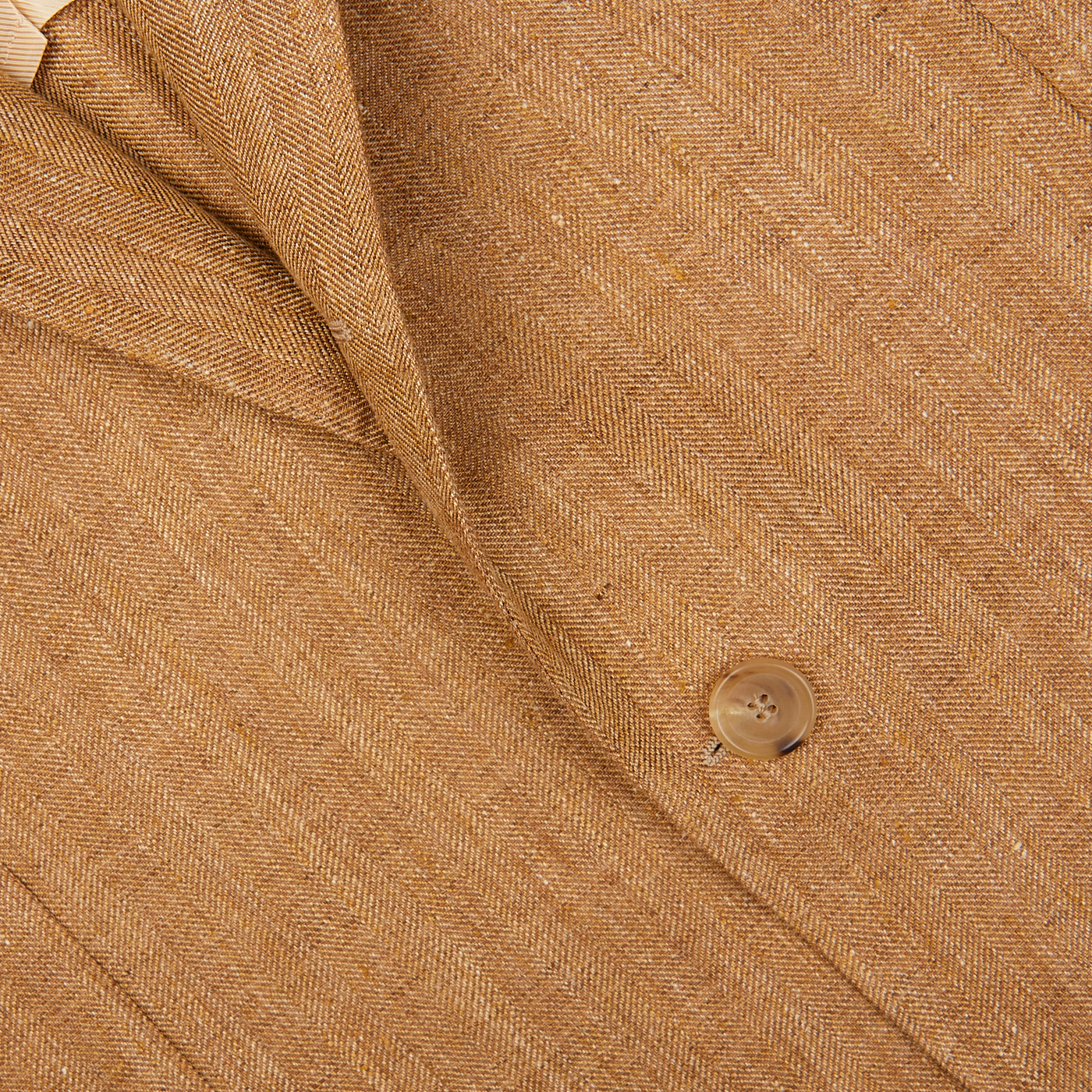 Close-up of a textured Tobacco Brown Herringbone Pure Linen Suit fabric with a single button from De Petrillo.