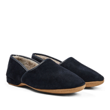 A pair of Derek Rose Navy Suede Sheepskin Closed-Back Slippers with a warm lining on a reflective surface.