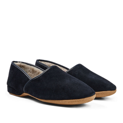 A pair of Derek Rose Navy Suede Sheepskin Closed-Back Slippers with a warm lining on a reflective surface.