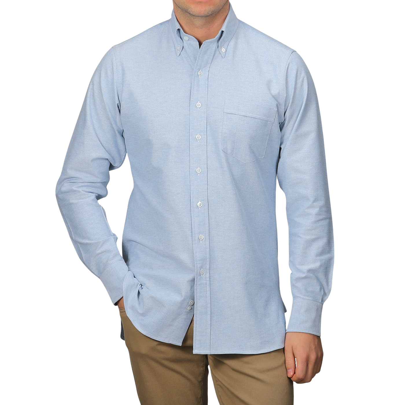 A person in a light blue Drake's Blue Classic Cotton Oxford BD Shirt, featuring a front pocket, and khaki pants stands against a plain gray background.