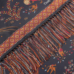 A close-up of the Navy Birds of Paradise Print Tubular Silk Scarf by Drake's showcases a fringed edge with a colorful and intricate pattern featuring animals, leaves, and geometric designs on a dark background. This exquisite scarf draws inspiration from the rich textile traditions of Como, Italy.