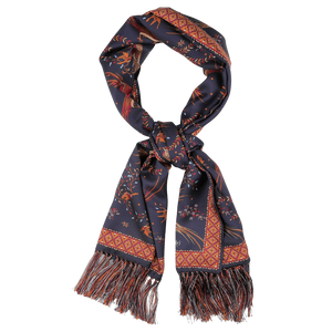 A navy silk scarf from Drake's, known as the "Navy Birds of Paradise Print Tubular Silk Scarf," displays intricate patterns in red and orange, complete with fringe at the ends.