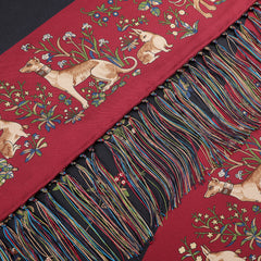 A silk scarf from Drake's, featuring an exquisite archival design with intricate unicorn patterns in navy and adorned with multicolored tasselled fringes, captures a unique elegance.