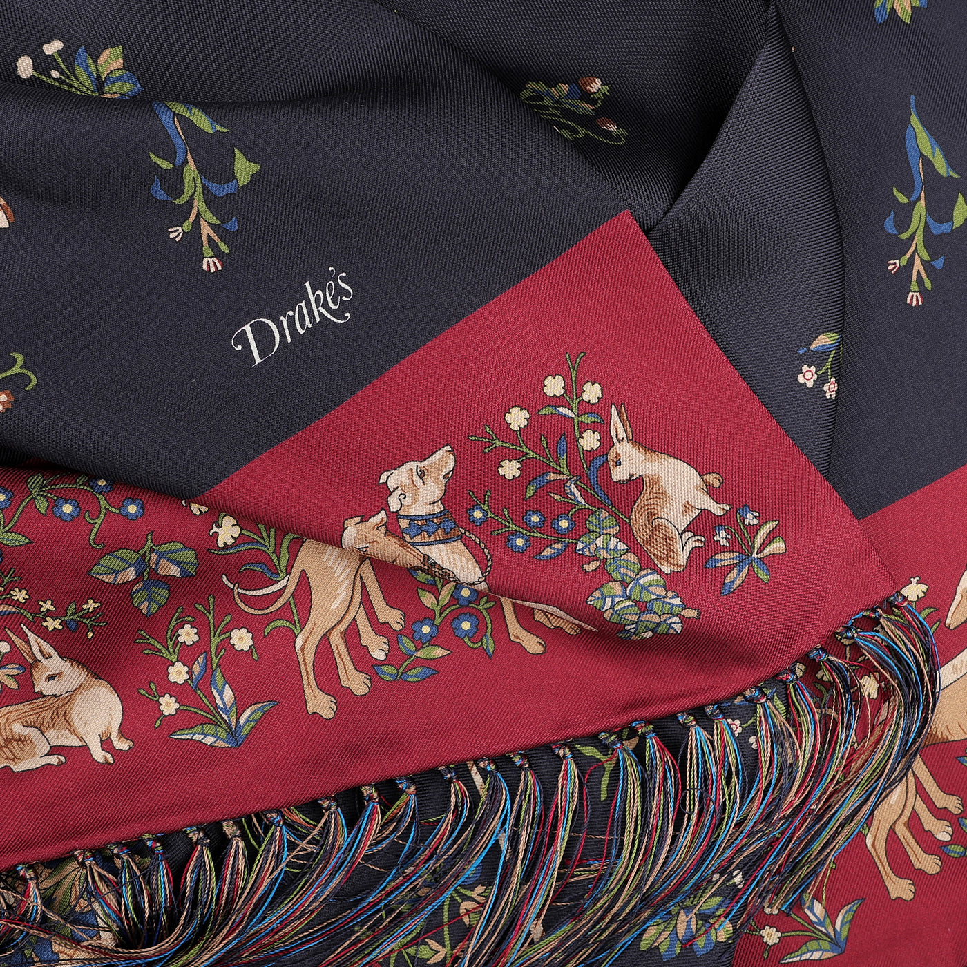 The Navy Unicorn Print Tubular Silk Scarf by Drake's showcases whimsical unicorn illustrations and floral motifs, finished with tasselled fringes on one edge.