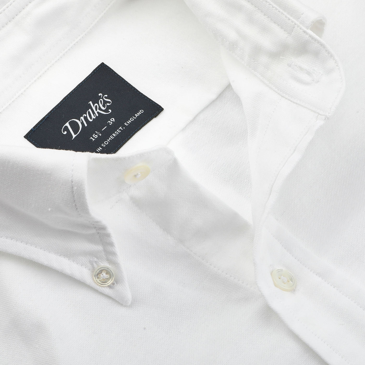 The White Classic Cotton Oxford BD Shirt by Drake's, with a visible label displaying the brand name and size, exemplifies British handmade elegance.