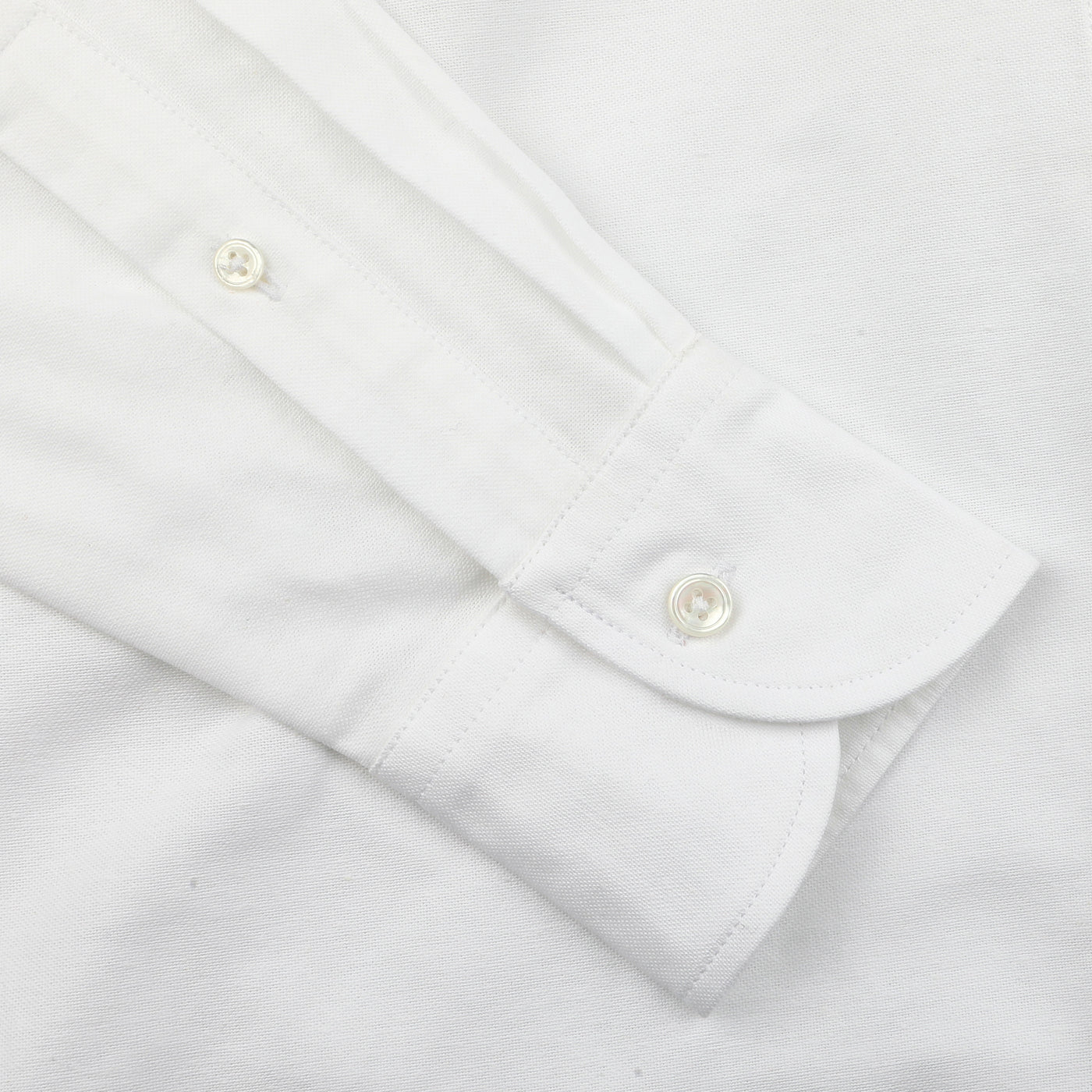 Close-up of a sleeve from Drake's White Classic Cotton Oxford BD Shirt, featuring a buttoned cuff that epitomizes British handmade tailoring craftsmanship.