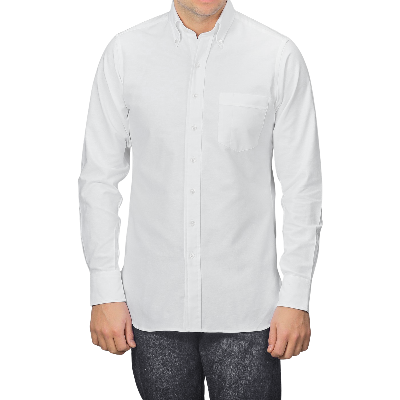 A man in a Drake's White Classic Cotton Oxford BD Shirt with a pocket on the left and dark jeans stands against a gray background.