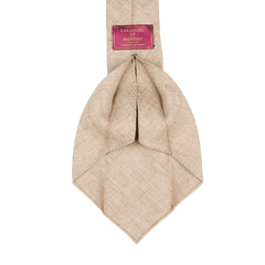 A Beige Melange 7-Fold French Linen Tie made by Dreaming Of Monday with a pink label on it.