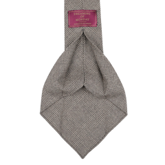 The Brown Glen-Check 7-Fold Wool Flannel Tie from Dreaming Of Monday is expertly handmade in Sweden and features a purple tag with white text, adding a touch of elegance.