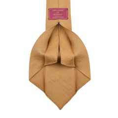 The Château Noir Ochre 7-Fold French Linen Tie by Dreaming Of Monday boasts a beige texture with a red label stating "Dreaming of Monday" and "Handmade in Italy," offering artisanal charm to elevate your wardrobe.