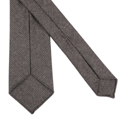 A Dark Brown Dogtooth 7-Fold Wool Flannel Tie by Dreaming Of Monday, showcasing a brown and gray houndstooth pattern, elegantly folded against a white background.