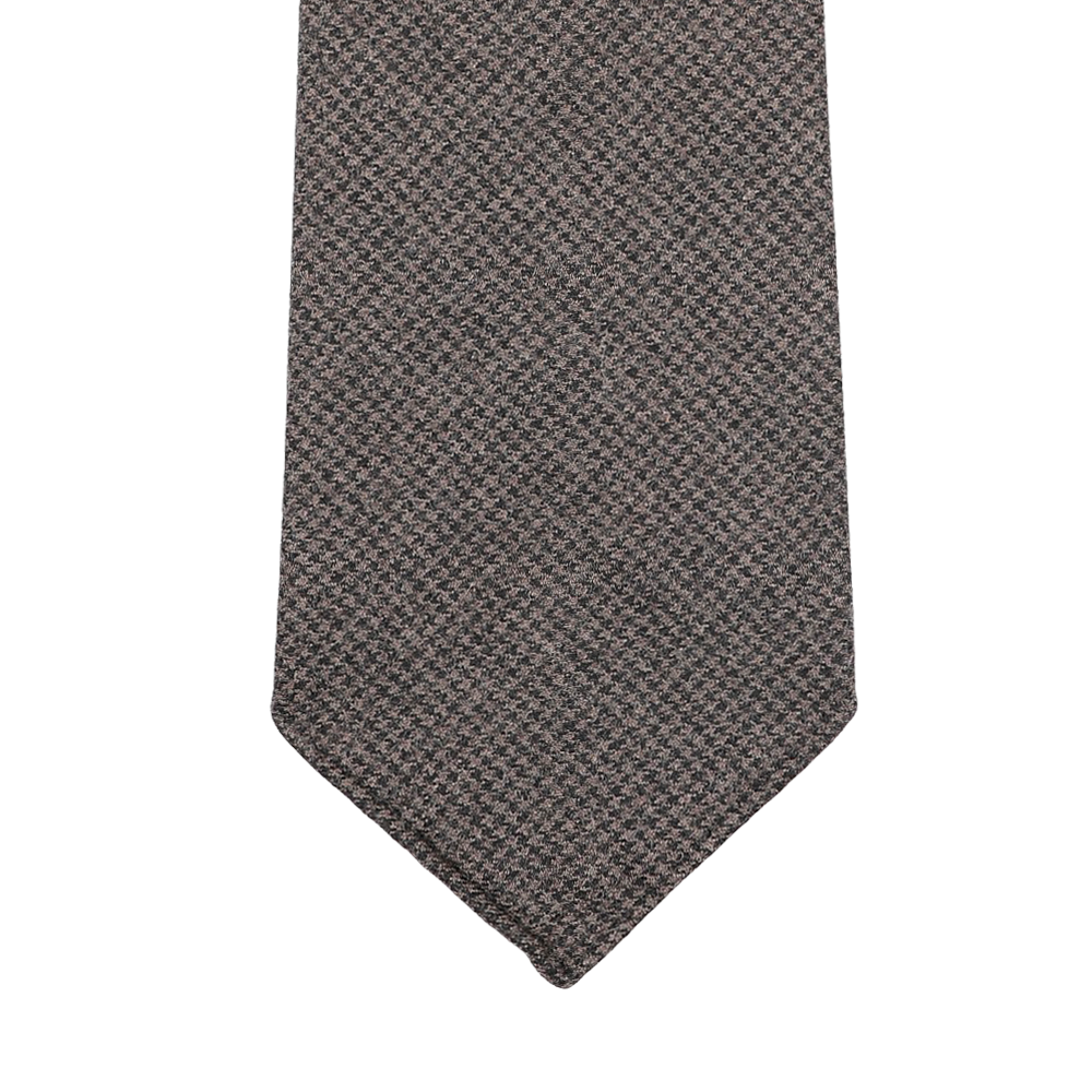 Introducing the Dark Brown Dogtooth 7-Fold Wool Flannel Tie by Dreaming Of Monday, a handmade Swedish creation that boasts an elegant checkered pattern, beautifully showcased against a white backdrop.