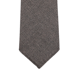 Introducing the Dark Brown Dogtooth 7-Fold Wool Flannel Tie by Dreaming Of Monday, a handmade Swedish creation that boasts an elegant checkered pattern, beautifully showcased against a white backdrop.