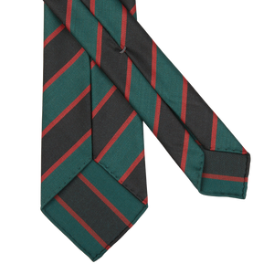 Two Green Black Regimental 7-Fold Wool Ties by Dreaming Of Monday, featuring green, red, and black diagonal stripes, lying overlapping on a white background.