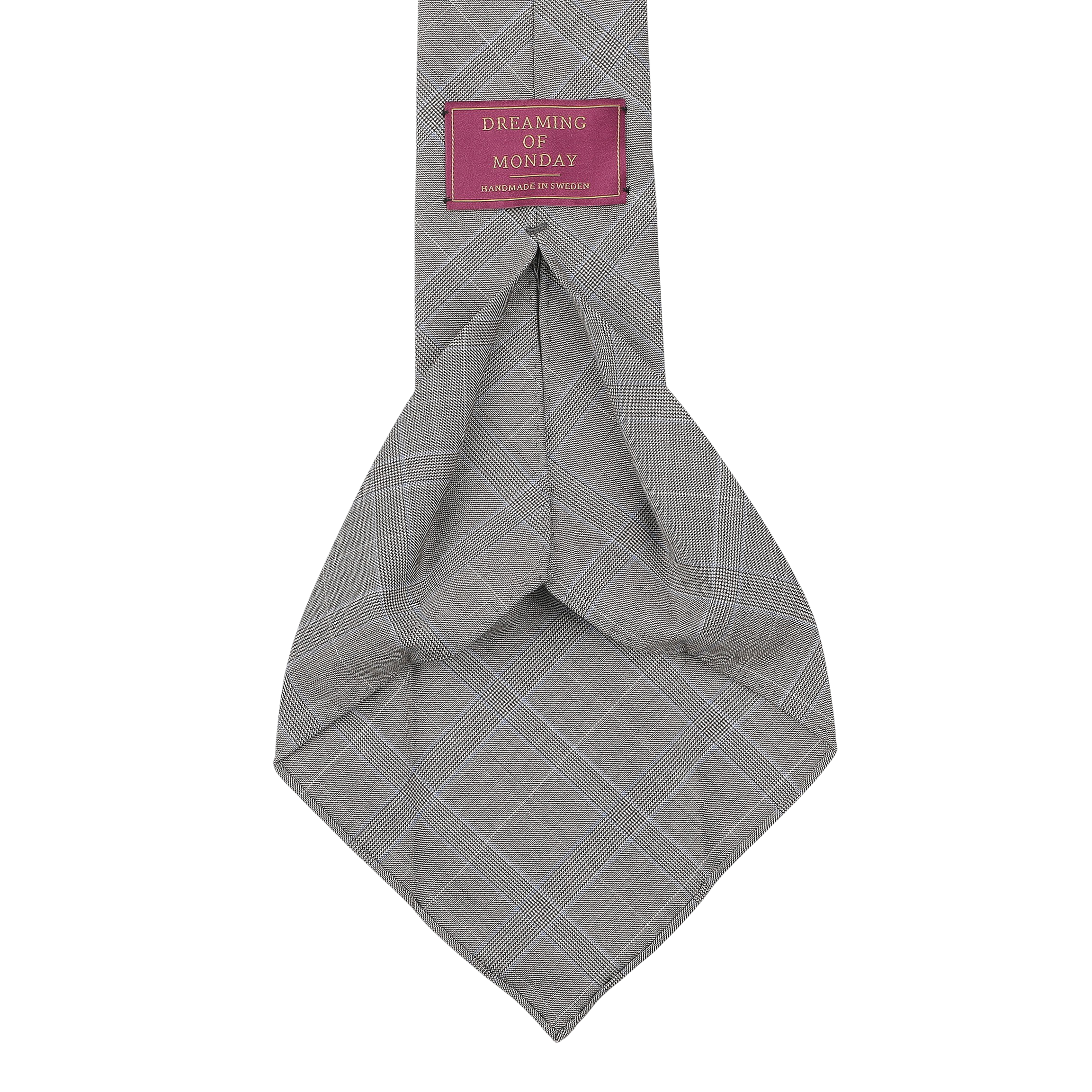 The Grey Blue Glen Plaid 7-Fold Vintage Wool Tie, handmade in Sweden, features a label with the text "Dreaming Of Monday" in pink and white.