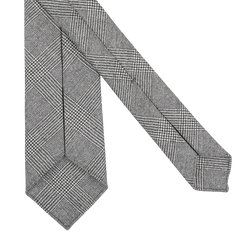 Close-up of the Grey Glen-Checked 7-Fold Wool Flannel Tie by Dreaming Of Monday, featuring a sophisticated grey-black glencheck design with an intricate black and white houndstooth pattern on a pristine white backdrop.