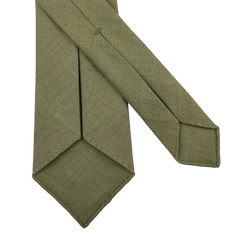 Close-up of the Jardin Provençal Green 7-Fold French Linen Tie by Dreaming Of Monday, showcasing its diagonal weave pattern, laid flat on a white surface.